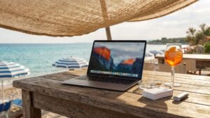 Laptop auf Holztisch am Strand unter Sonnenschirm